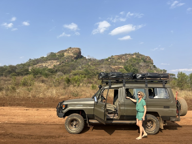 A woman standing next to her 4x4 while driving a self-drive itinerary in Kenya